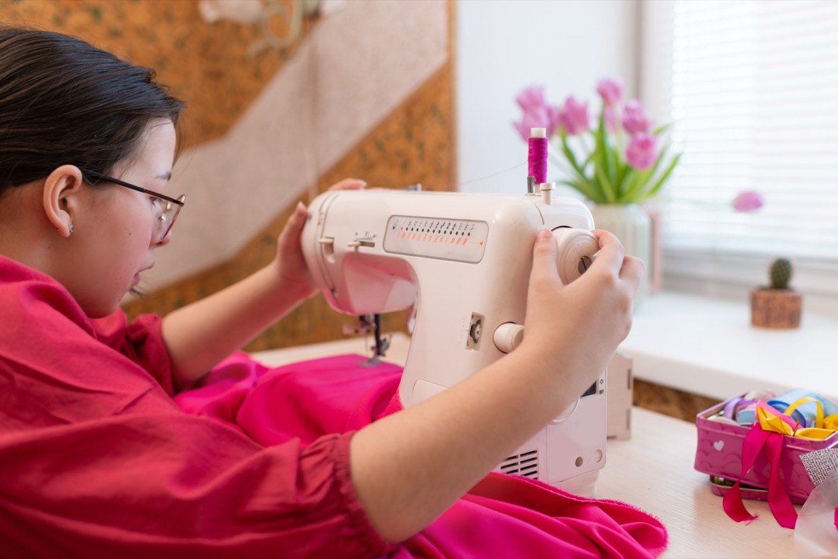 Girl sewing a pink dress on a sewing machine