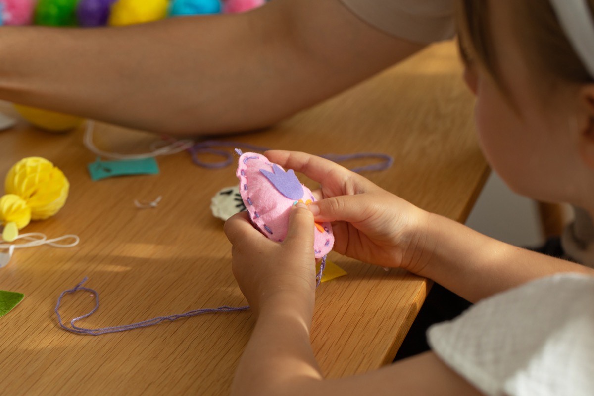 Child making a handmade felt toy with colourful thread